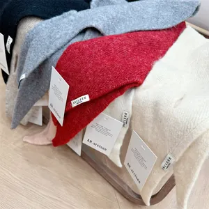 Close-up detail of soft wool knit triangle scarves in red, white, and grey with tags