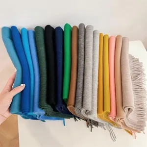 Detailed view of assorted colorful solid soft wool scarves featuring elegant fringe edges