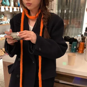 Vue détaillée d'une écharpe chenille en tricot orange vif et duveteuse sur un mannequin