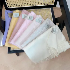 Detailed view of 100% Australian wool scarves in various pastel colors on a chair.