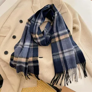 Close-up detail of a soft blue and beige plaid wool scarf with long decorative fringe.