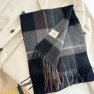 Macro view of a classic plaid wool scarf with fringe detailing on a beige coat.
