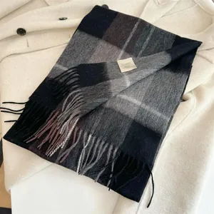 Detailed close-up of a 100% wool plaid scarf with fringes and material care label