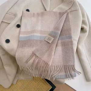 Detail view of a 100% Australian wool plaid scarf with fringes on a beige coat