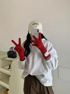Red knitted touchscreen gloves worn by model in a cozy lifestyle setting
