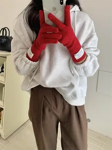 Cozy red knitted five-finger gloves with touch screen design worn by model for winter style