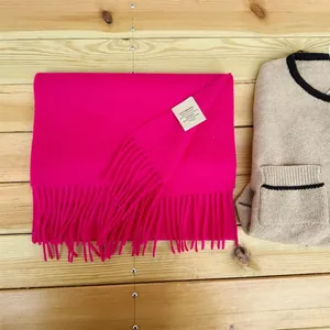 Close-up detail shot of 100% Australian wool label on a bright pink fringed scarf