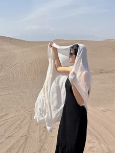 Dettaglio di uno scialle parasole in lino beige leggero usato come foulard da deserto.