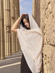 Modella con scialle beige effetto lino davanti a colonne del deserto per il sole