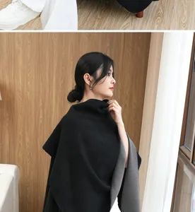 Side view of a thick reversible black and grey knit shawl poncho worn by a model.