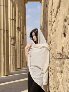 Scialle da viaggio beige in cotone e lino indossato come foulard in esterni