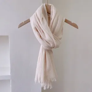 Primo piano di un'elegante sciarpa beige in cotone e lino con frange