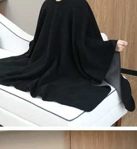 Close-up of a premium black oversized knit shawl cape draped on a white sofa.