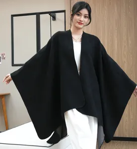 Elegant black knitted oversized shawl cape poncho for women in an indoor setting