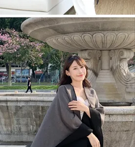 Elegant model wearing a grey and black oversized knit shawl in an outdoor park setting
