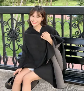Elegant black reversible shawl cape worn by a woman in an outdoor park setting