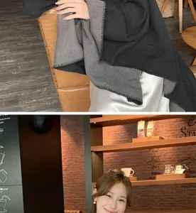 Detailed view of a soft grey and black two-tone wool shawl poncho worn in a cafe setting