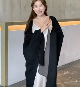 Model wearing a dual-tone black and grey wool-like shawl poncho over a white slip dress