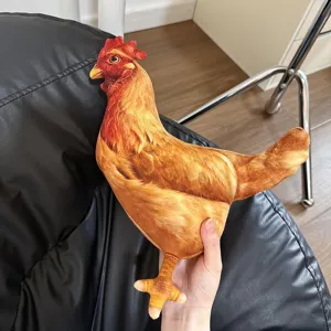 Vue détaillée d'un oreiller en peluche réaliste en forme de poule brune dans la main