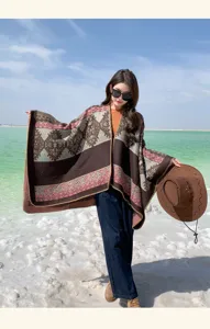 Model wearing a large bohemian patterned shawl poncho by a scenic turquoise salt lake.