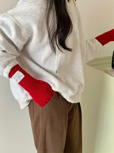 Close-up of red long knit gloves with thumb hole on female model wearing hoodie