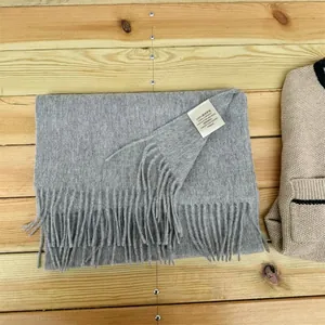 Detailed view of 100% Australian wool grey scarf with tassel fringe on wood background