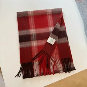 Close-up of red plaid 100% wool scarf with soft tassels and care label