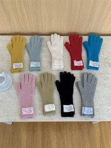 Assortment of colorful knitted wool gloves with fabric labels displayed on stone