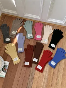 Variety of colorful knitted winter gloves displayed on a warm wooden floor.
