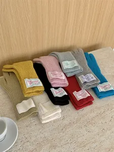 Detail of colorful knitted wool gloves with Grove Woolwear patch label in various shades.