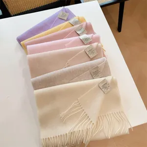Collection of folded 100% Australian wool scarves in soft pastel colors with tassels