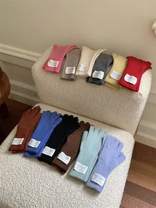 Assorted colors of soft knit winter gloves arranged on a textured white chair