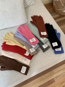 Detailed view of colorful long knit gloves with white labels on a soft grey sofa