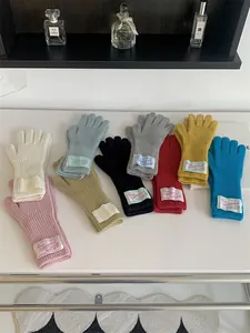 Detailed view of colorful knitted wool gloves with vintage fabric labels on a white desk.