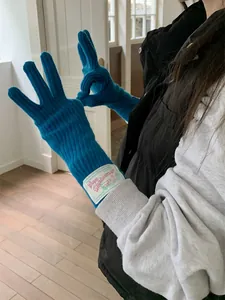 Detailed view of bright blue knit wool gloves featuring a vintage style woven wrist label