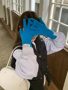Close-up of vibrant blue knitted wool gloves featuring a decorative cloth label on the wrist