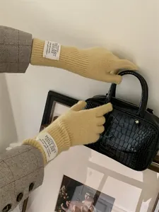 Detail view of yellow knit winter gloves featuring a minimalist white label on wrist