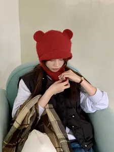 Detail view of a cozy red knitted balaclava with bear ears worn by an Asian woman