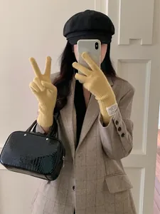 Detailed view of yellow knitted touchscreen gloves worn with a stylish autumn outfit