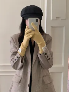 Detailed view of stylish yellow knitted long gloves worn by model in mirror selfie