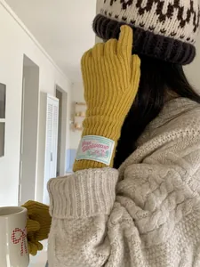 Macro view of yellow knitted wool glove with a vintage decorative fabric label.