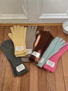 Detail shot of various colorful knitted winter gloves neatly displayed on a rustic floor