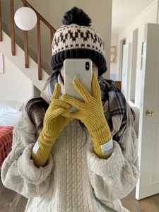 Detail view of stylish yellow wool knitted gloves with a decorative cloth label