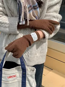 Detail of brown knitted winter gloves with touchscreen finger opening and woven label