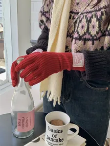 Detailed lifestyle view of warm red knit wool gloves featuring a vintage fabric label accent