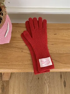 Macro view of red knitted wool gloves with vintage cloth label on a rustic wooden bench