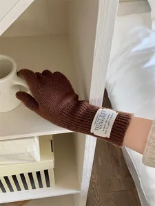 Close-up of soft brown knitted gloves with wrist patch in a minimalist home setting