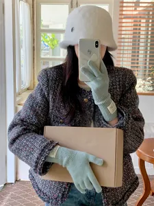 Close-up of cozy mint green knit gloves worn by a woman in a stylish winter outfit