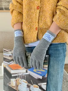 Detailed view of grey ribbed knitted wool gloves featuring a vintage style woven label