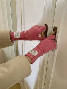 Detail of pink ribbed knit five-finger gloves with aesthetic cloth label on wrist